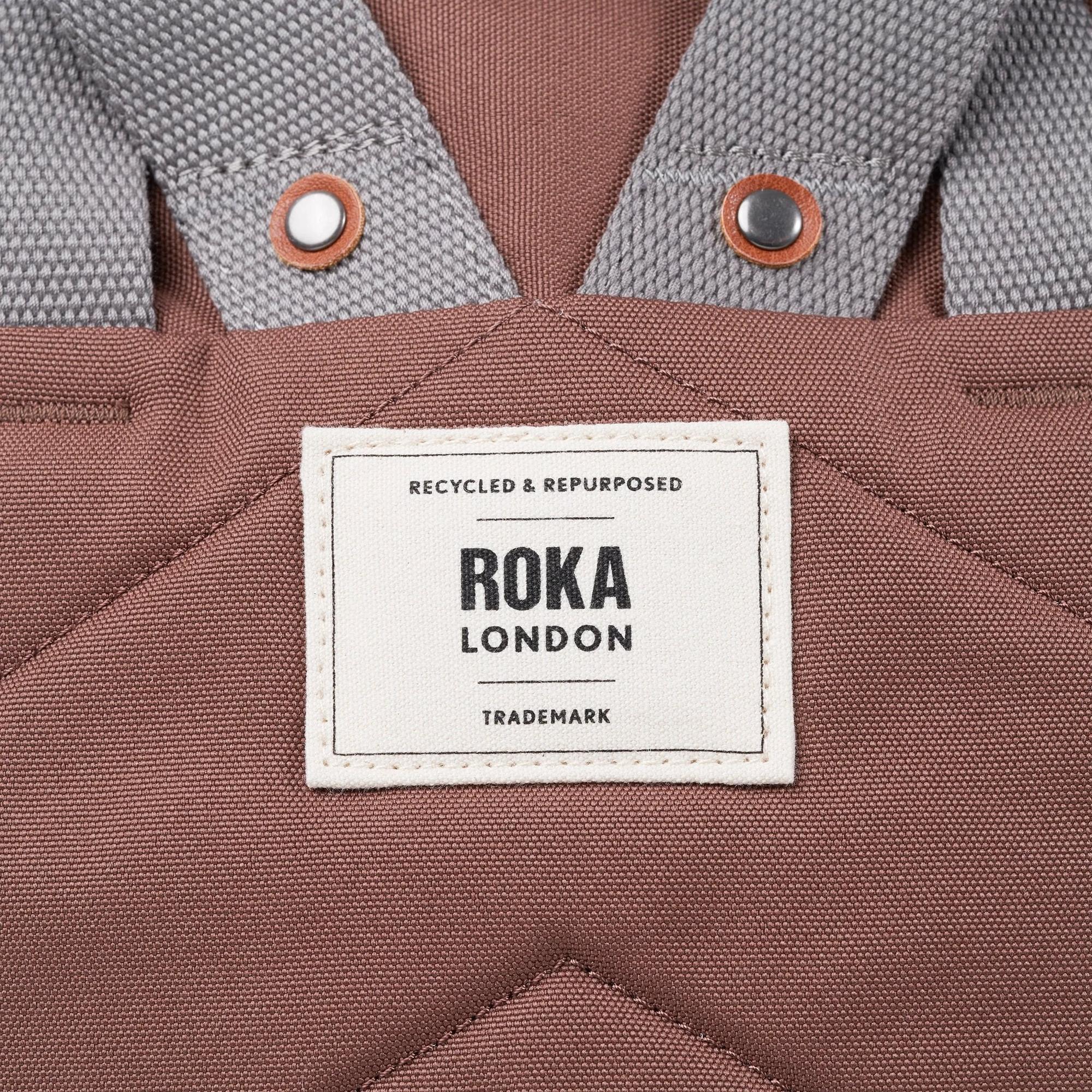Roka Finchley A Coco recycled canvas tote bag with gray straps and metal snaps, featuring a white label and brown fabric exterior.