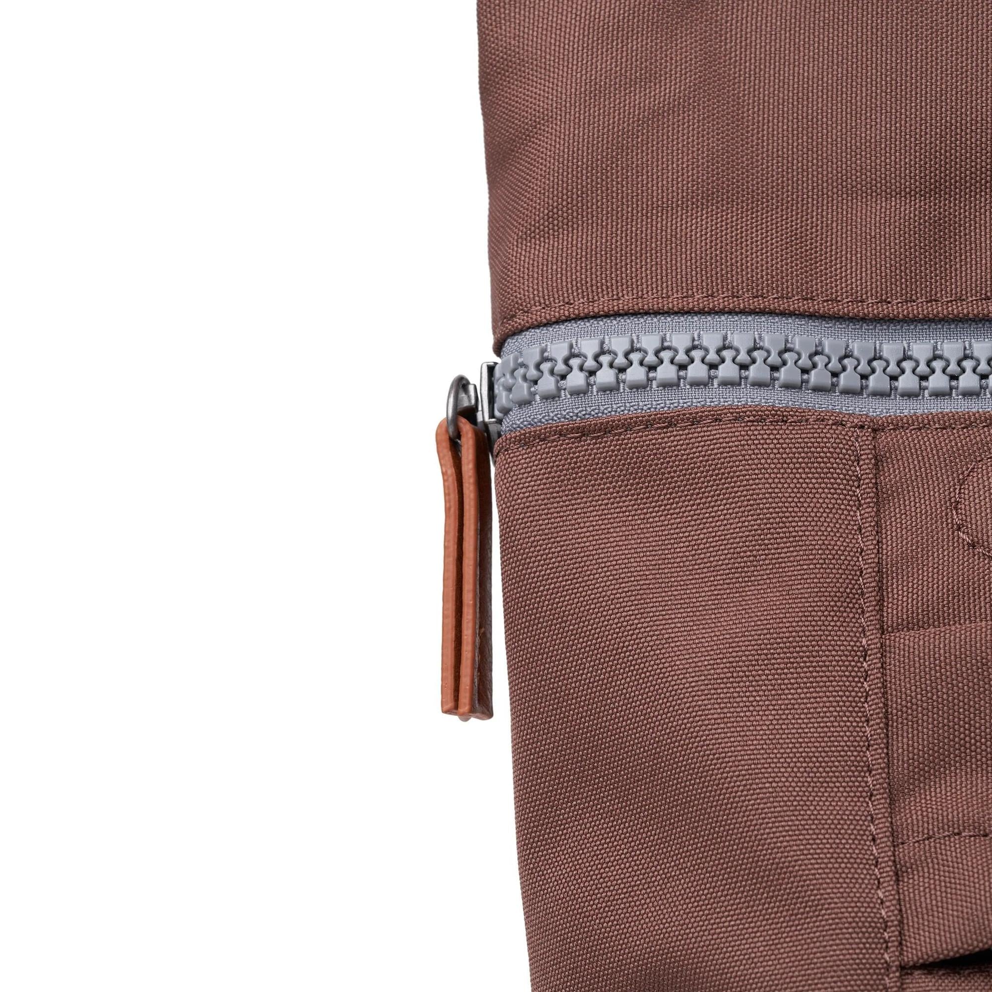 Roka Finchley A Coco recycled canvas backpack with zip closure, brown fabric, and leather zipper pull.