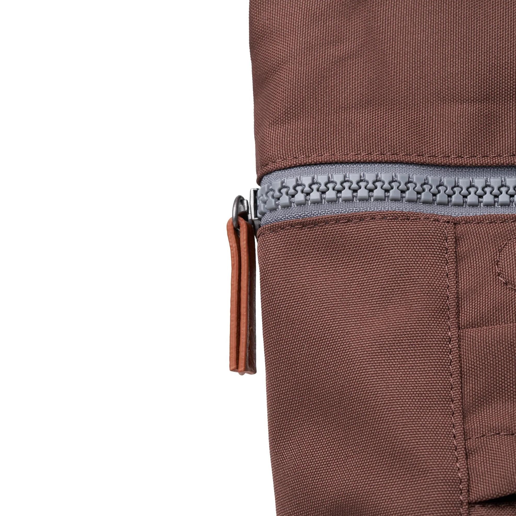 Roka Finchley A Coco recycled canvas bag with a grey zipper and tan leather pull tab, close-up detail of durable textured fabric.