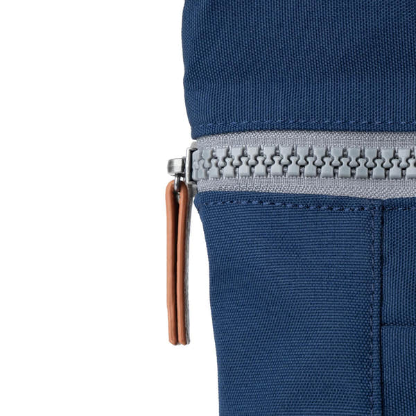 Roka Finchley backpack with blue recycled canvas fabric, silver zipper, and leather pull tab.