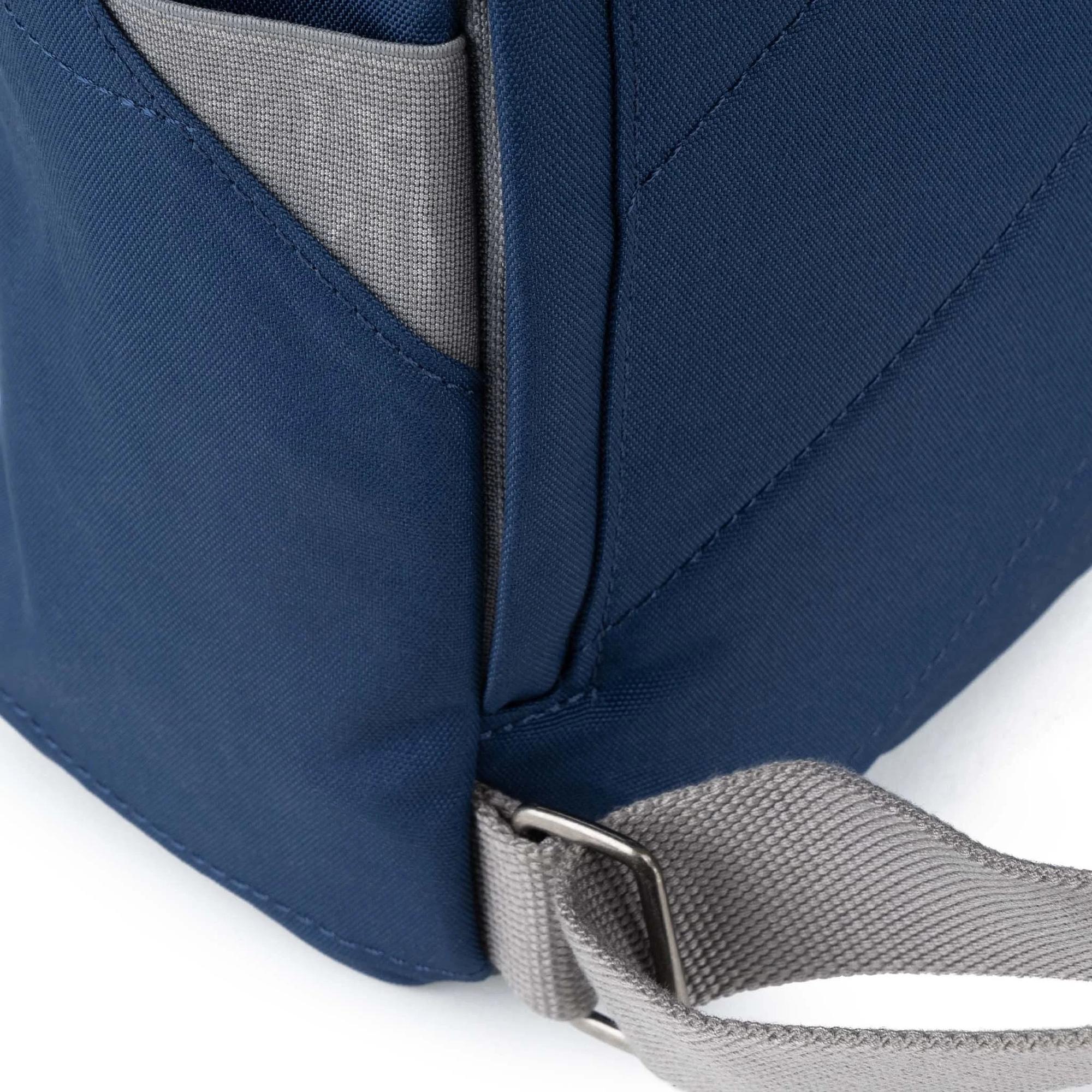 Roka Finchley backpack in crisp blue recycled canvas with gray strap and side pocket, close-up shot highlighting material and design.