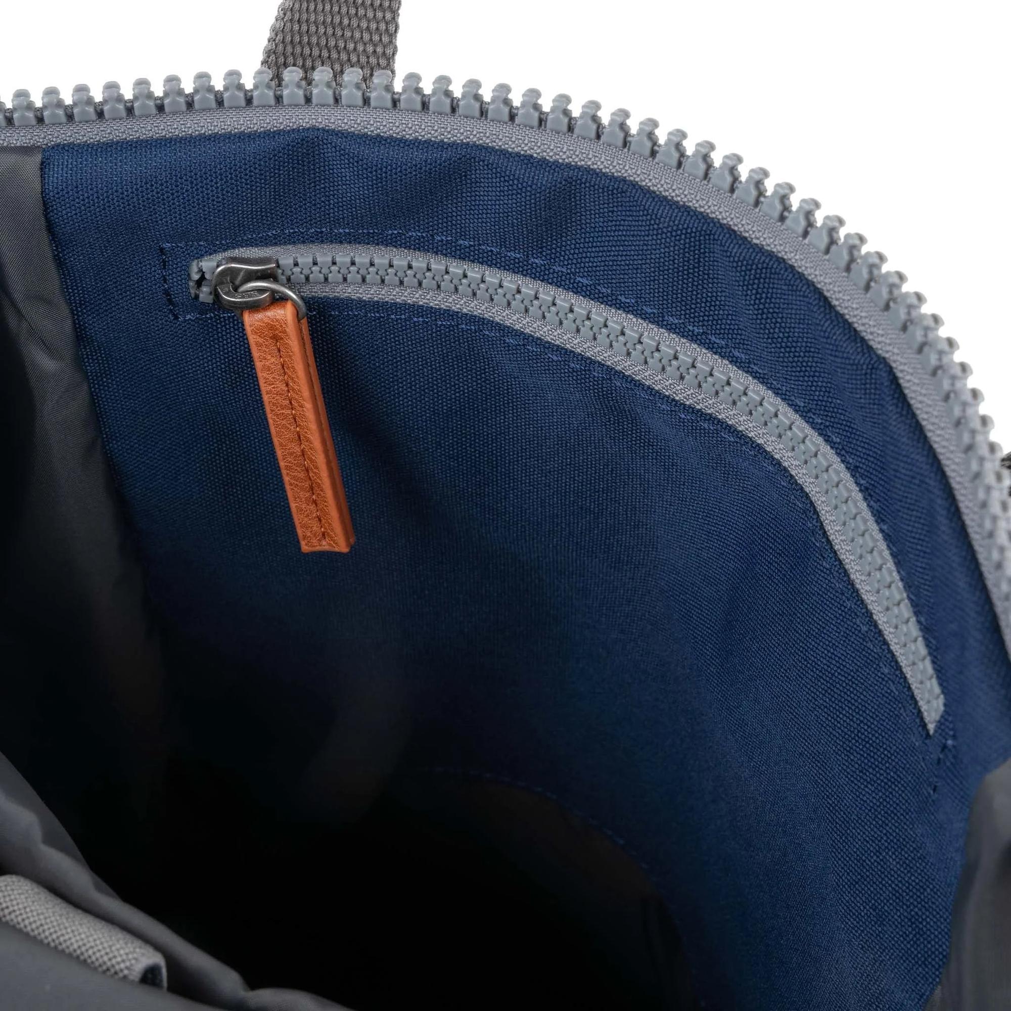 Roka Finchley blue recycled canvas backpack interior with zippered pocket and tan leather zipper pull.