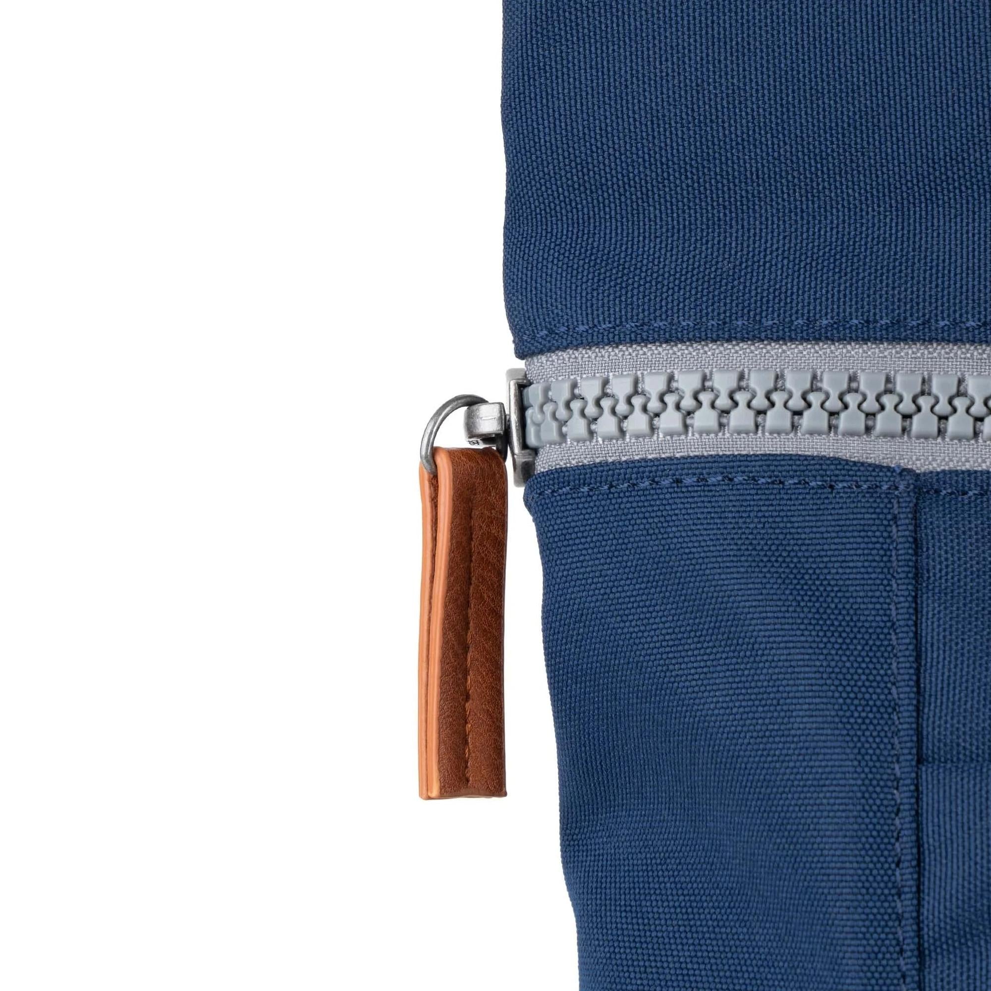 Roka Finchley blue recycled canvas bag with a silver zipper and leather zipper pull, close-up detail.