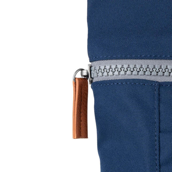 Roka Finchley blue recycled canvas bag with a silver zipper and leather zipper pull, close-up detail.