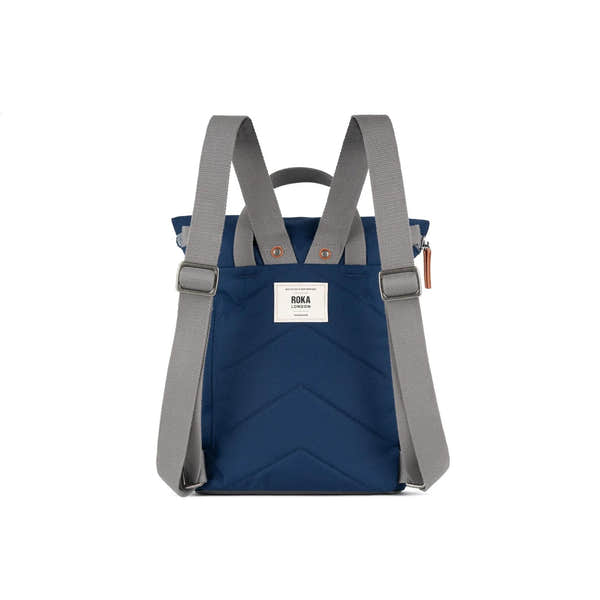 Roka Finchley backpack in crisp blue recycled canvas with gray adjustable straps and handle, front label, and modern design.