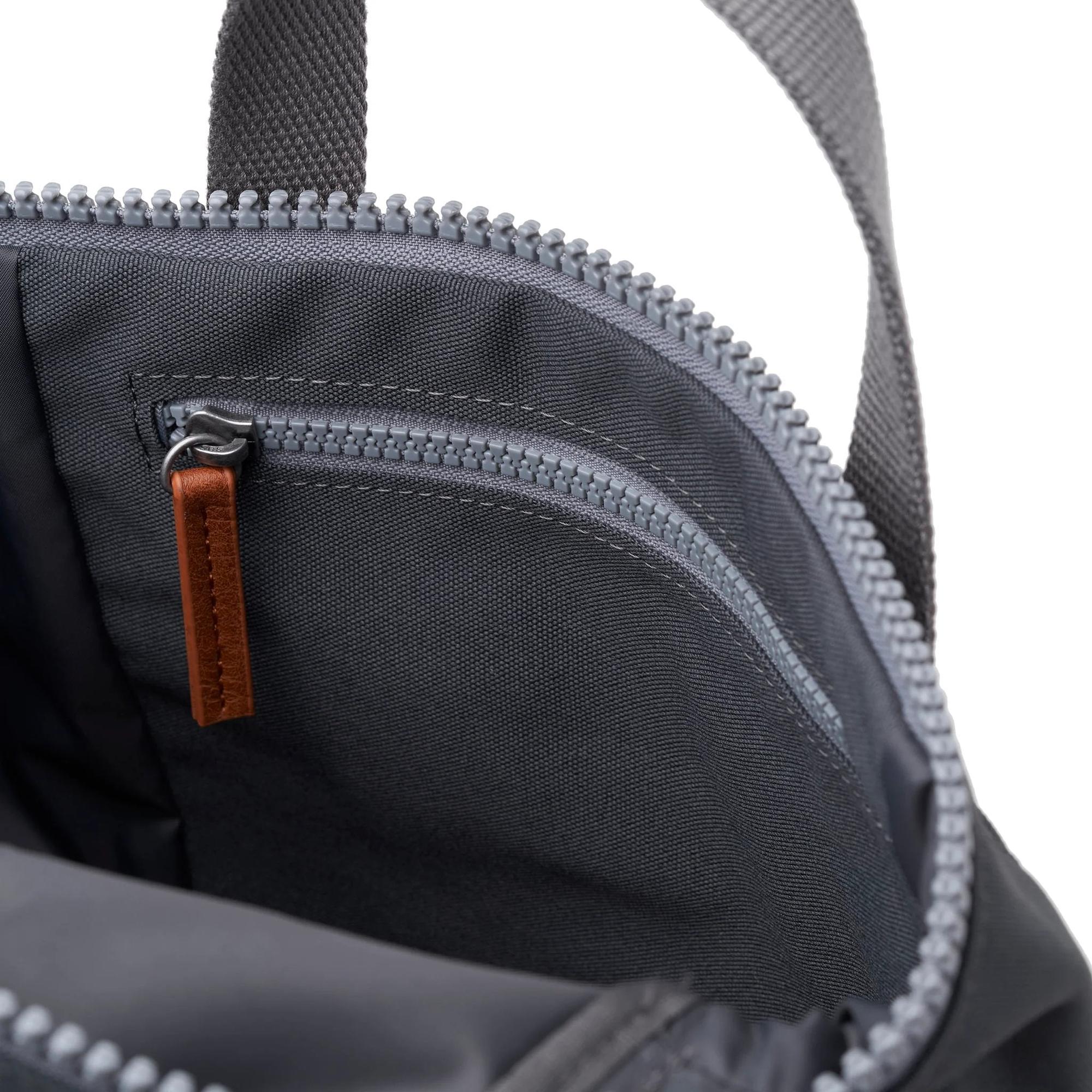 Close-up of Roka Finchley black recycled canvas backpack interior with zippered compartments and brown leather zipper pull.