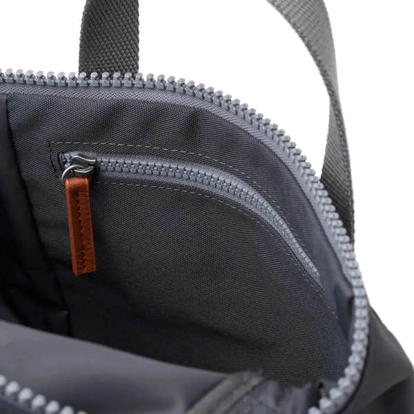 Close-up of Roka Finchley black recycled canvas backpack interior with zippered compartments and brown leather zipper pull.