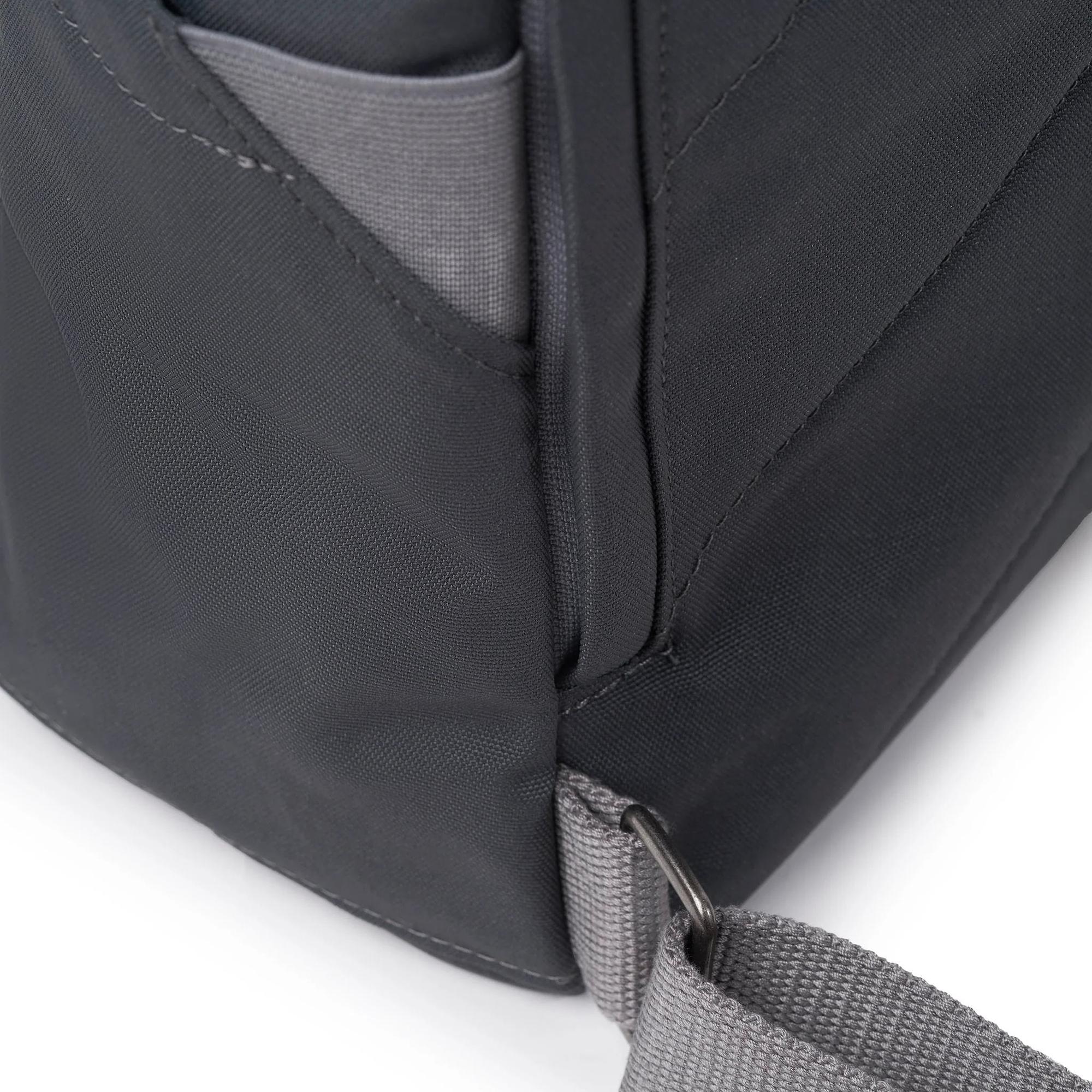 Roka Finchley A Faded Black Recycled Canvas backpack with gray strap and front pocket detail.