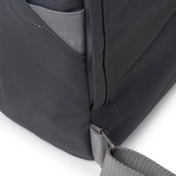 Roka Finchley A Faded Black Recycled Canvas backpack with gray strap and front pocket detail.