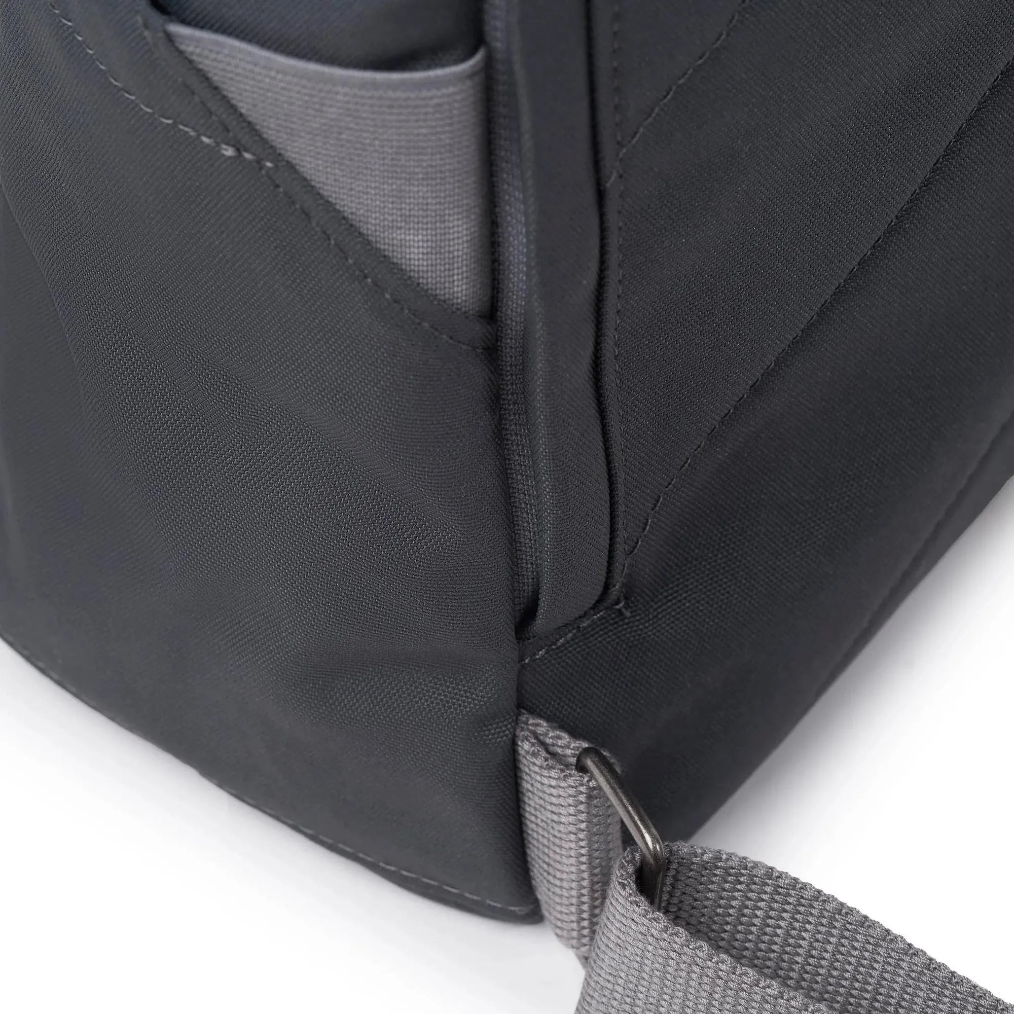 Roka Finchley A Faded Black Recycled Canvas backpack with gray strap and front pocket detail.