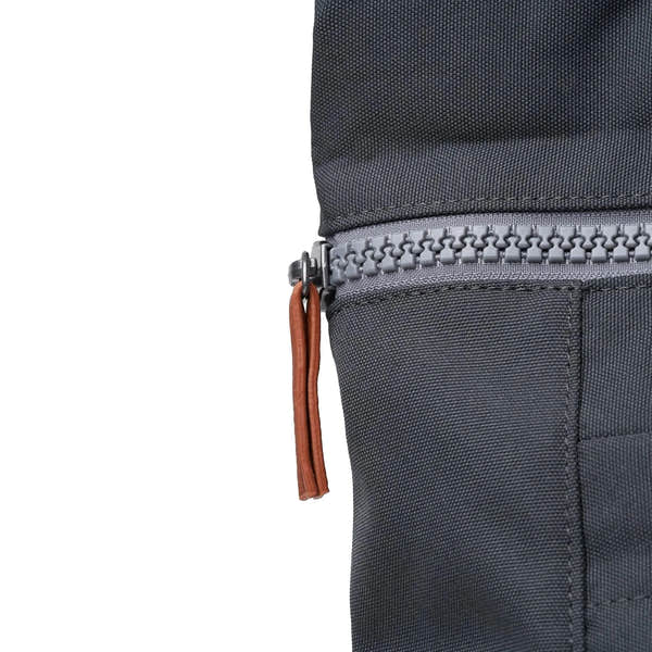 Roka Finchley A Faded Black Recycled Canvas backpack with a gray zipper and brown leather pull tab.