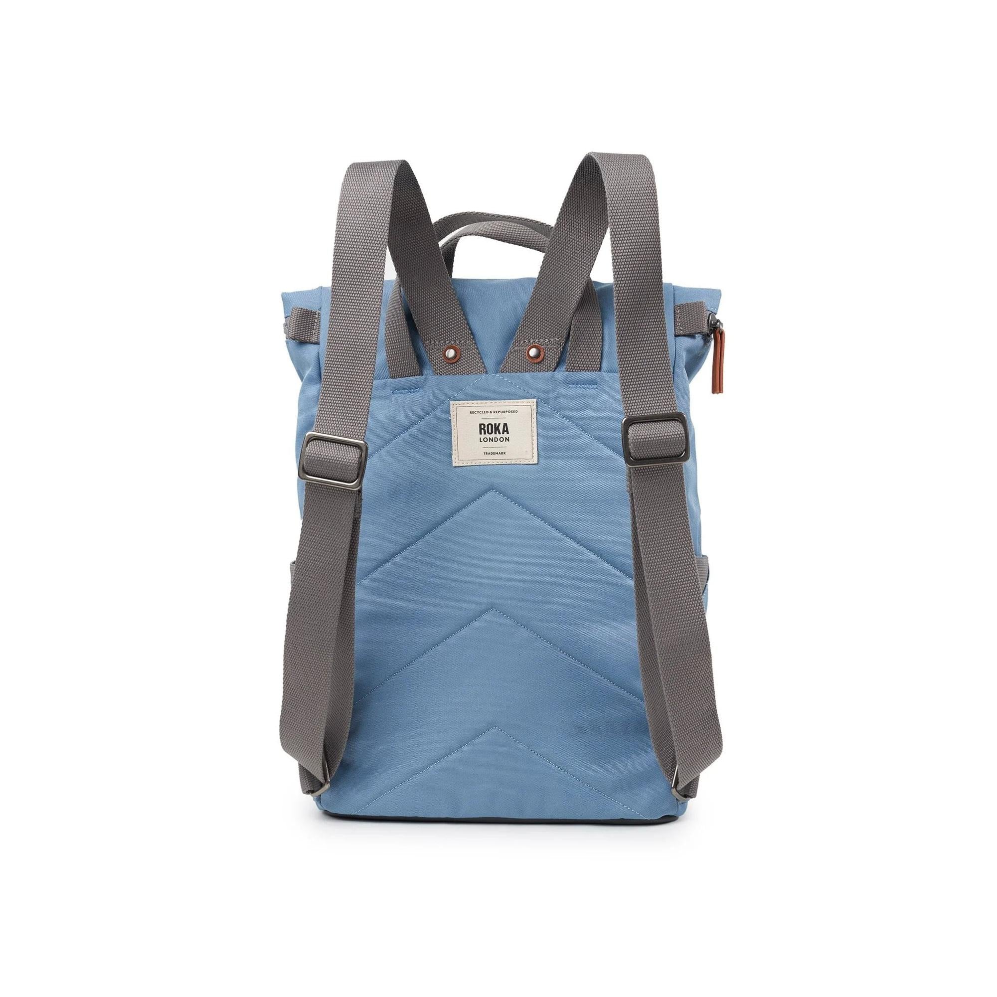 Roka Finchley backpack in retro blue recycled canvas with grey adjustable straps and front label, stylish eco-friendly design.
