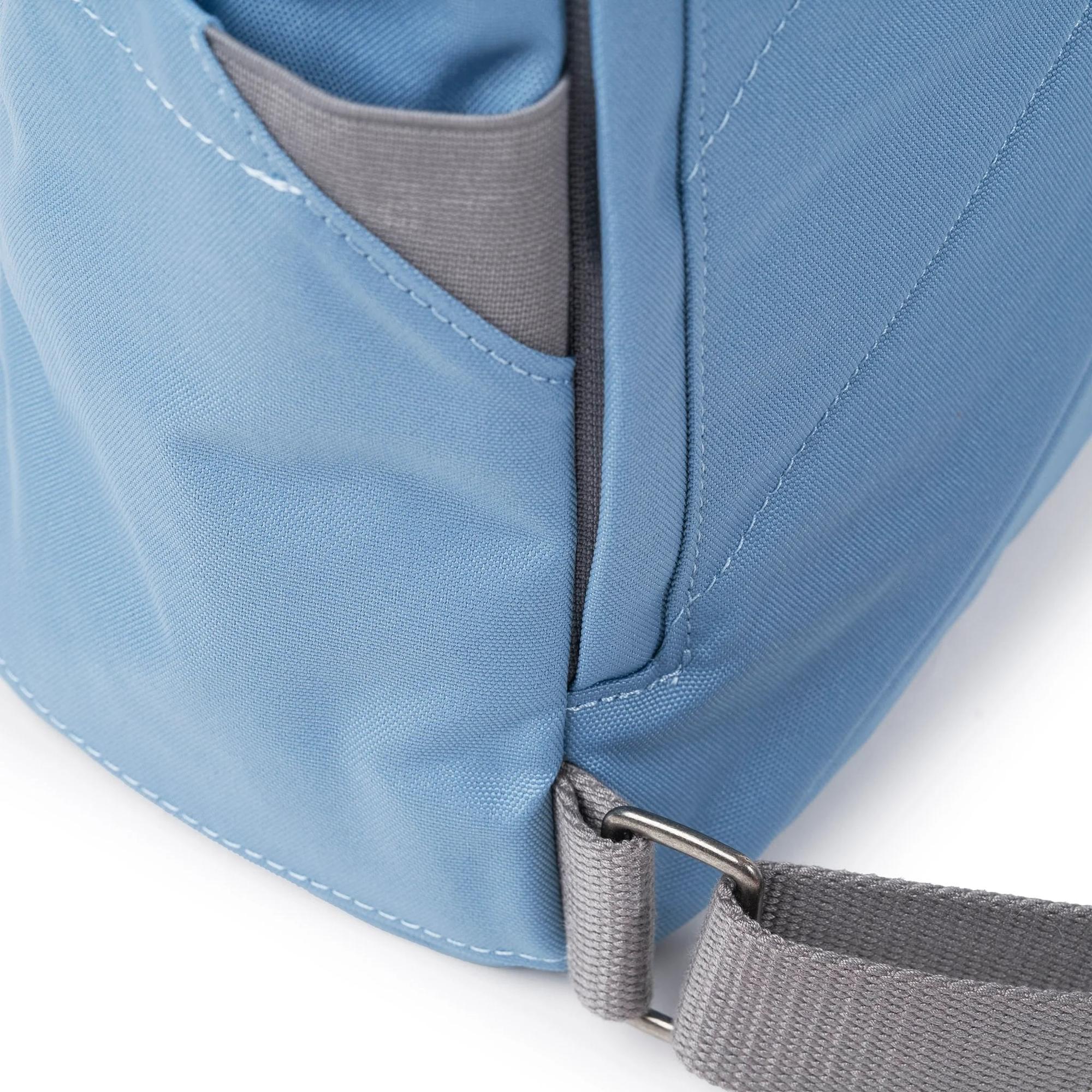 Roka Finchley A Retro Blue Recycled Canvas backpack with grey strap detail and front pocket.