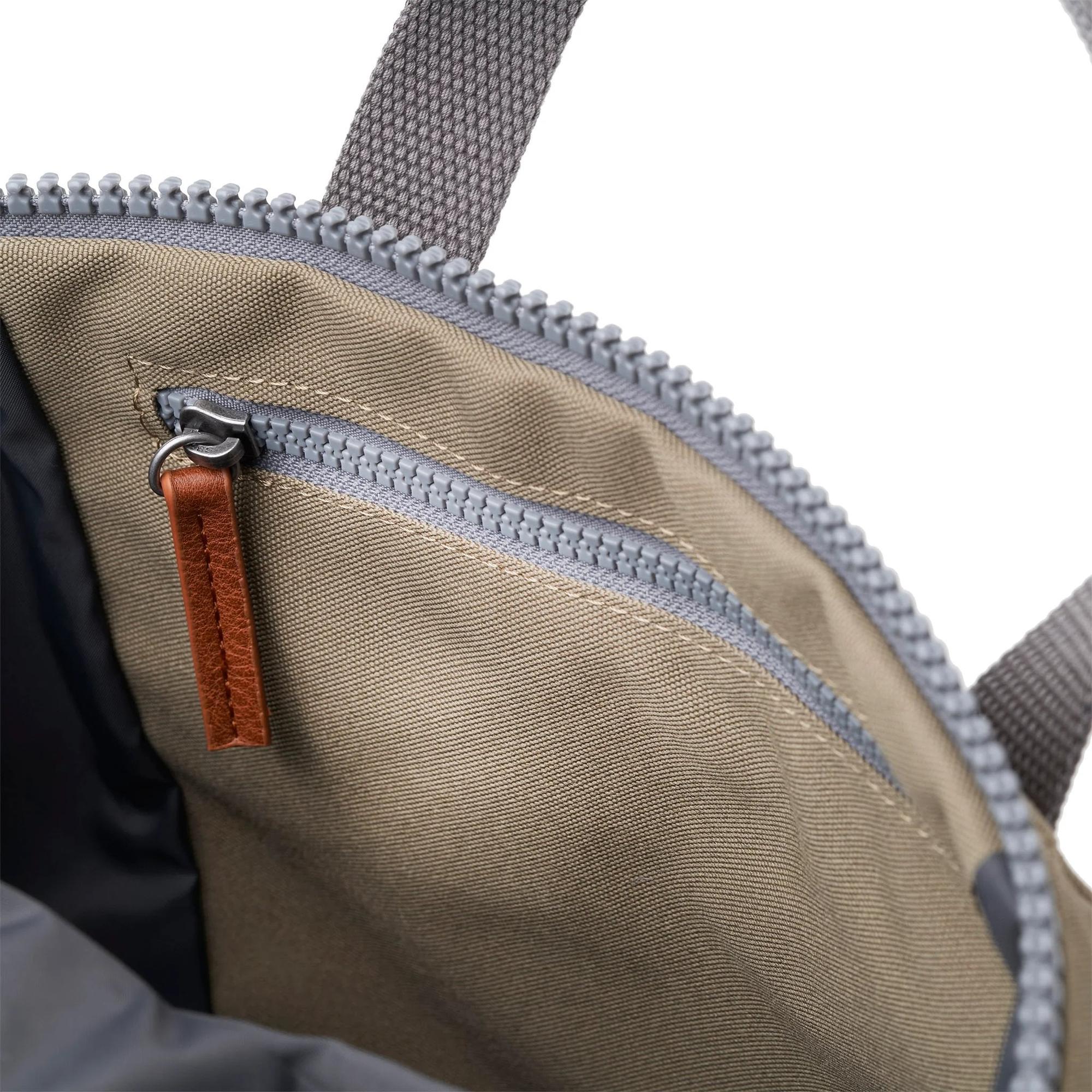 Roka Finchley A Taupe Recycled Canvas backpack interior with zippered pocket and brown leather pull tab.