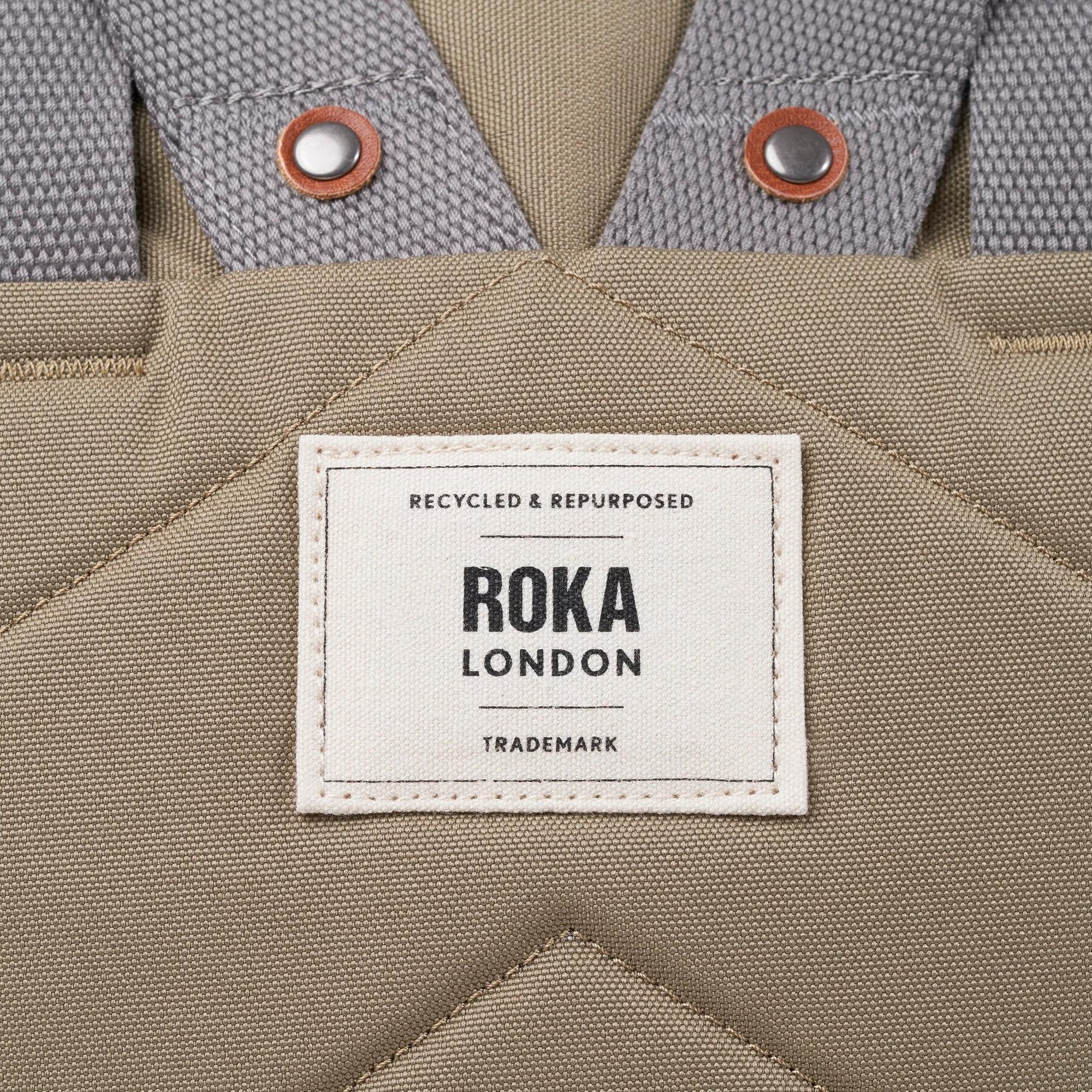 Roka Finchley taupe recycled canvas bag with fabric details and metal button accents.