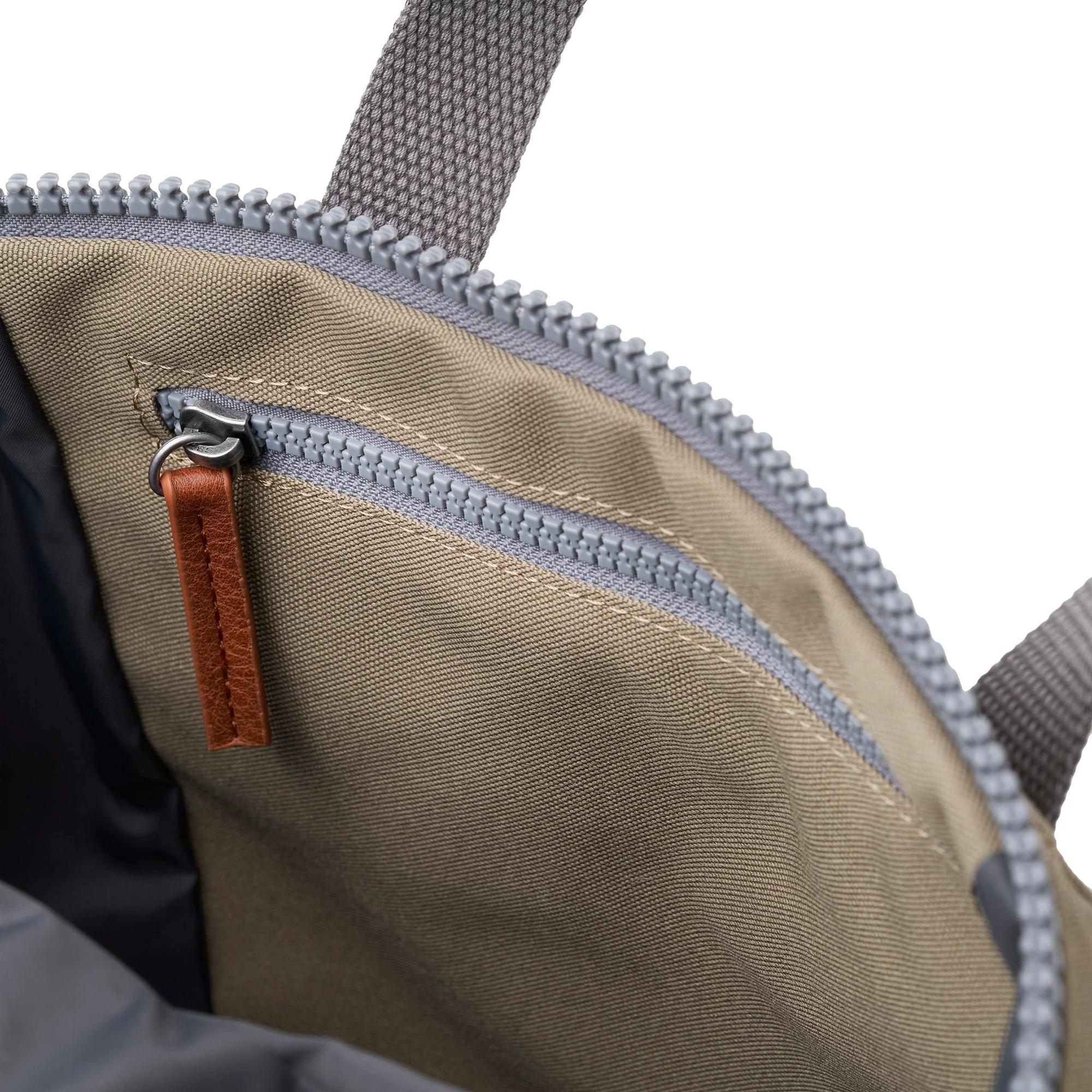 Roka Finchley A Taupe Recycled Canvas backpack interior with zippered pocket and leather pull tab, showcasing stylish and eco-friendly design.