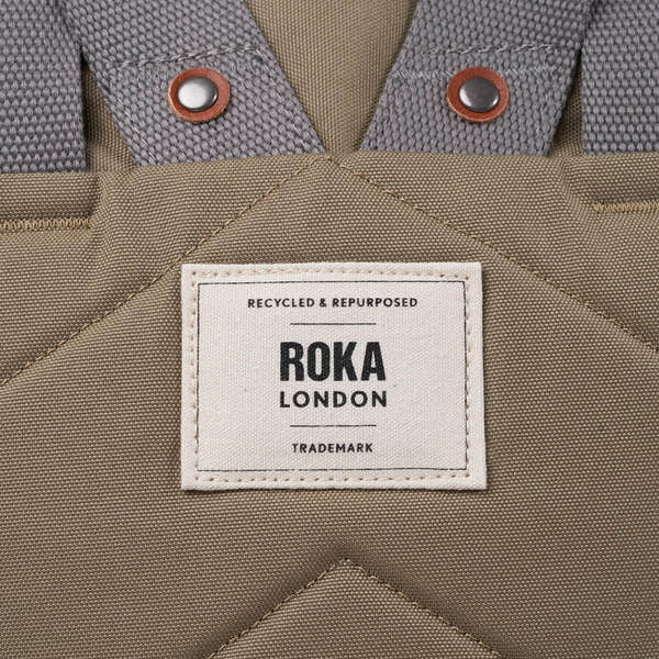 Roka Finchley taupe recycled canvas bag with fabric logo patch and dual metal snap buttons.