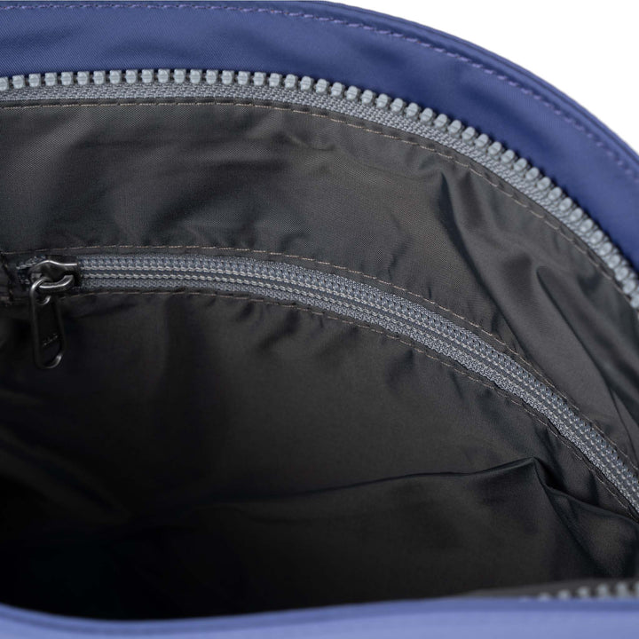 Roka Kennington B crossbody bag made of recycled nylon in indigo with zippered interior compartments.