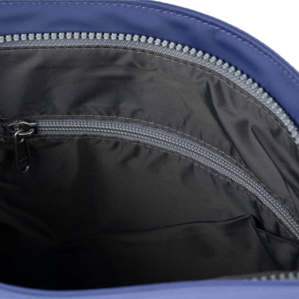 Roka Kennington B crossbody bag made of recycled nylon in indigo with zippered interior compartments.