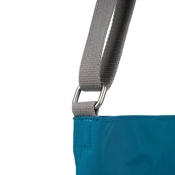 Roka Kennington B Crossbody bag in recycled nylon sapphire with grey adjustable strap and metal hardware close-up.