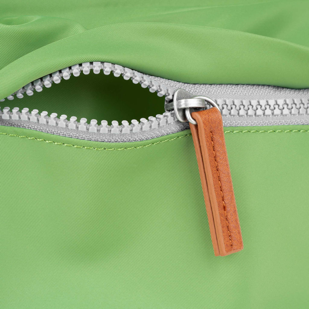 Roka Kennington B Kiwi Recycled Nylon backpack with silver zipper and tan leather pull tab, vibrant green color, eco-friendly material.