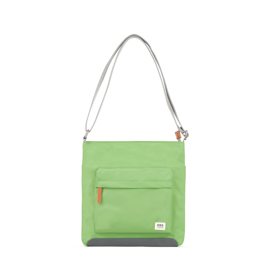Roka Kennington B Kiwi recycled nylon shoulder bag in bright green with front pocket, adjustable strap, and gray bottom detail.