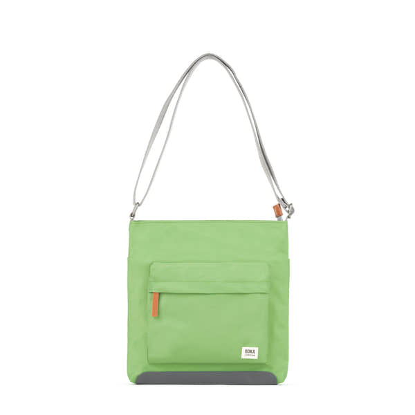 Roka Kennington B Kiwi recycled nylon shoulder bag in bright green with front pocket, adjustable strap, and gray bottom detail.