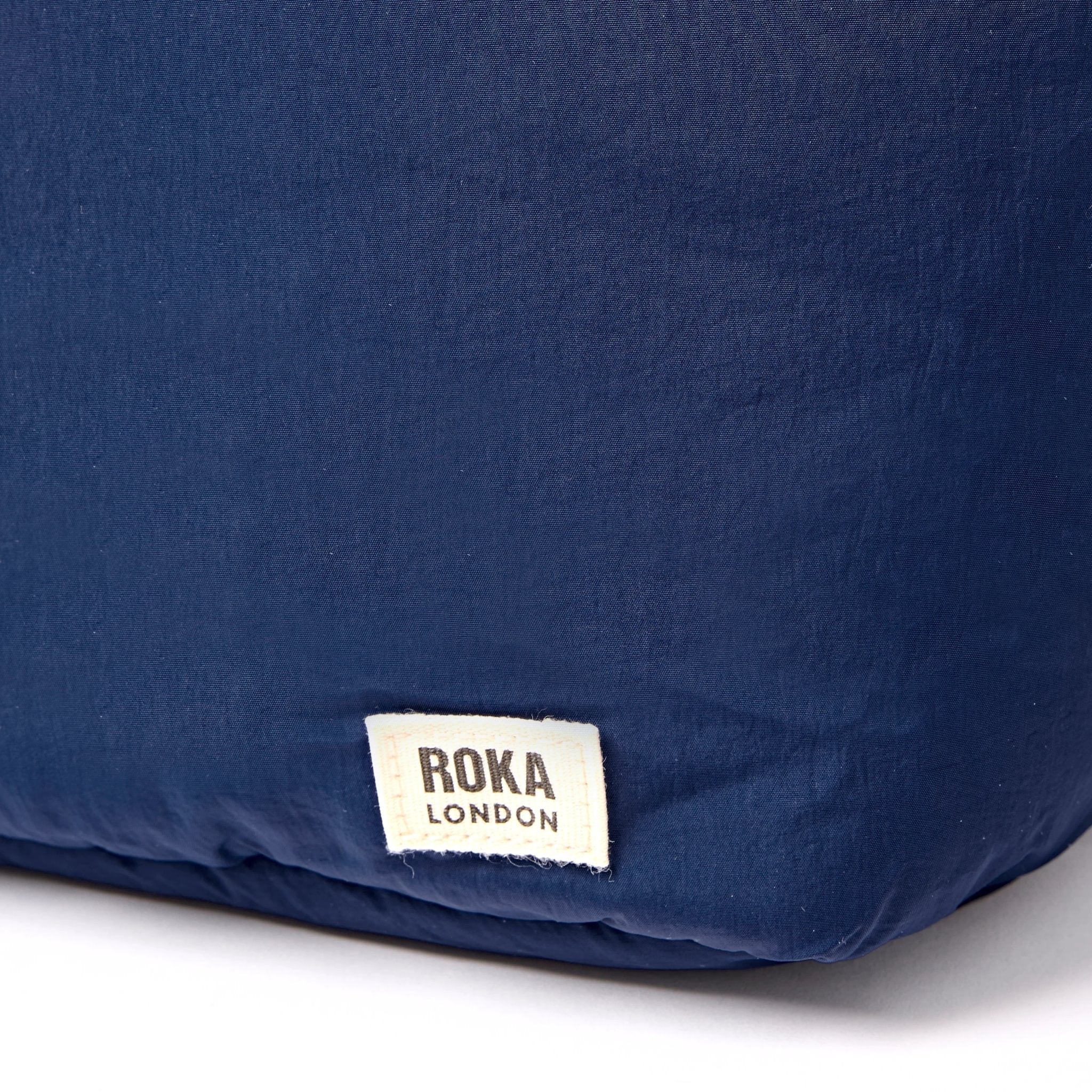 Roka Oxford Deep Cobalt Recycled Taslon Shoulder Bag, brand label detail.