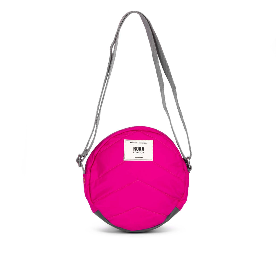 Roka Paddington B Candy small recycled nylon crossbody bag in bright pink with grey adjustable strap.