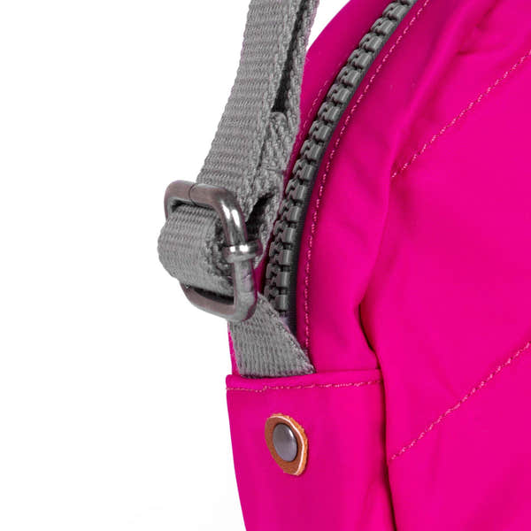 Roka Paddington B Small Recycled Nylon Backpack in bright pink with grey strap and zipper details.