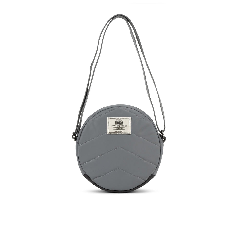 Roka Paddington B Stormy small recycled nylon round shoulder bag with zip closure and adjustable strap.