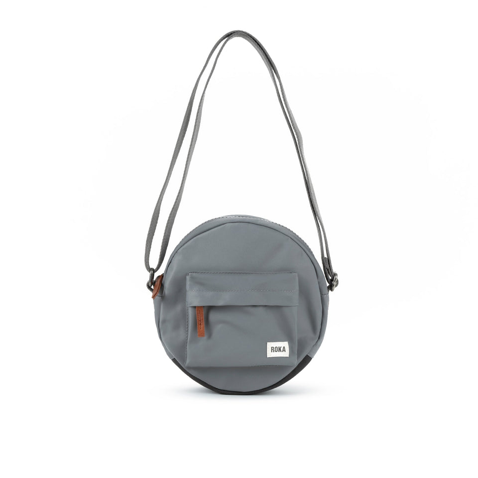Roka Paddington B Stormy small recycled nylon crossbody bag with front pocket and adjustable strap.