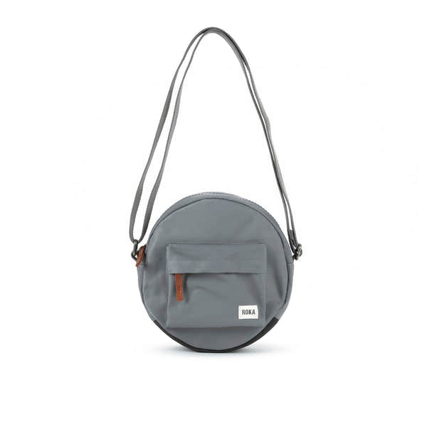 Roka Paddington B Stormy small recycled nylon crossbody bag with front pocket and adjustable strap.