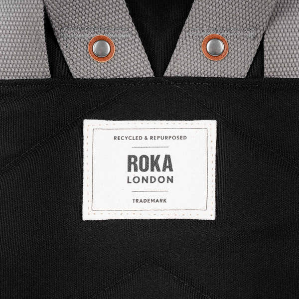 Roka Waterhouse recycled canvas ash zippered tote bag with grey and black fabric, metal snap accents, and a white branded label.
