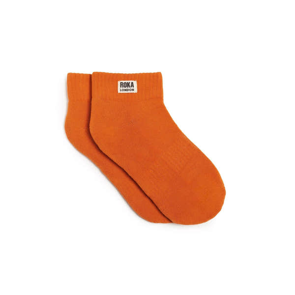 Roka Wembley burnt orange organic cotton one-size socks with logo tag on ankle, casual and comfortable footwear accessory.