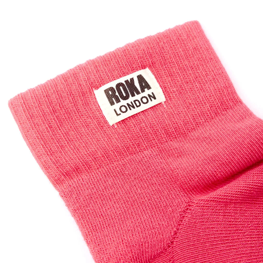 Roka London cotton socks in sugar coral color, featuring a close-up view of the ribbed fabric and branded label.