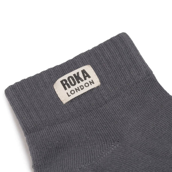 Roka Wembley Ladies organic cotton sock with "Roka London" label, in dark gray color, close-up view.