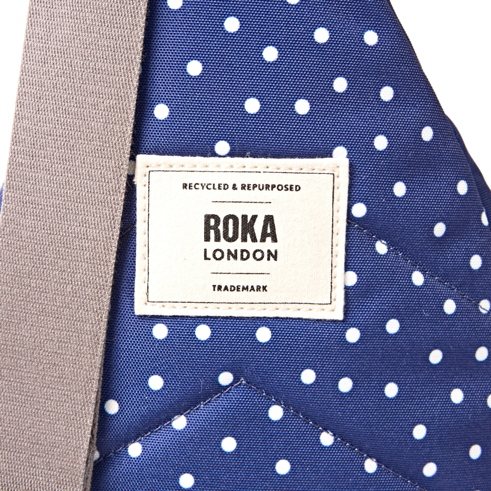 Roka Willesden Navy Polka Dot Recycled Canvas Sling Bag, brand label detail.