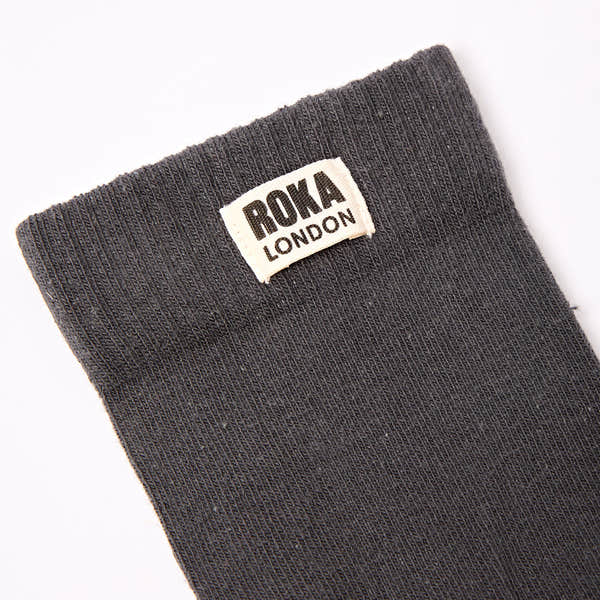 Roka London men's cotton crew sock in faded black, size one, with logo tag, close-up view.