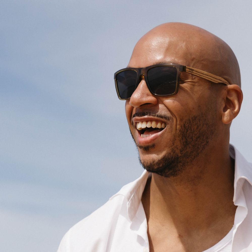 Man wearing SOEK Dalton khaki black polarised sunglasses with walnut arms, stylish eyewear, outdoor sunny setting.