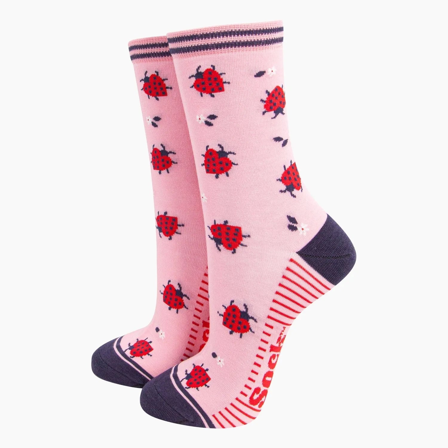 Pink bamboo socks with red ladybird and white flower patterns, navy toe and heel, and striped top edge.