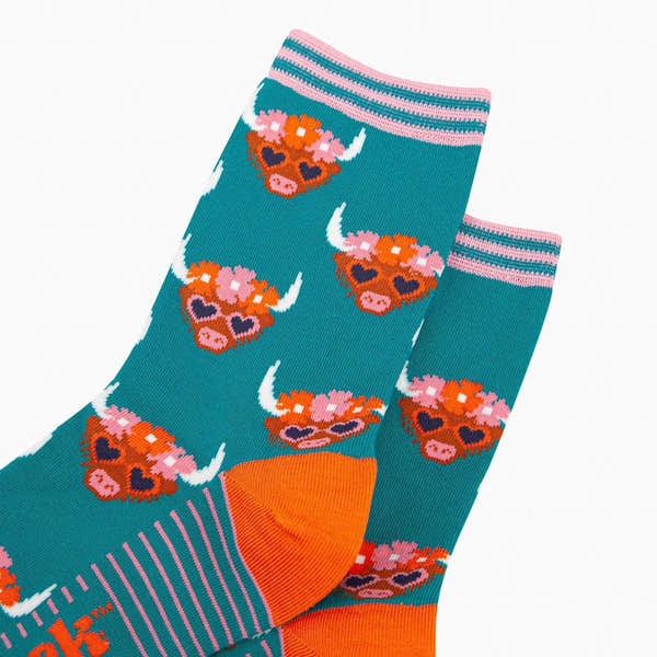 Teal bamboo socks featuring Highland cow with floral crown and heart-shaped sunglasses, striped pink accents, and orange heel detail.