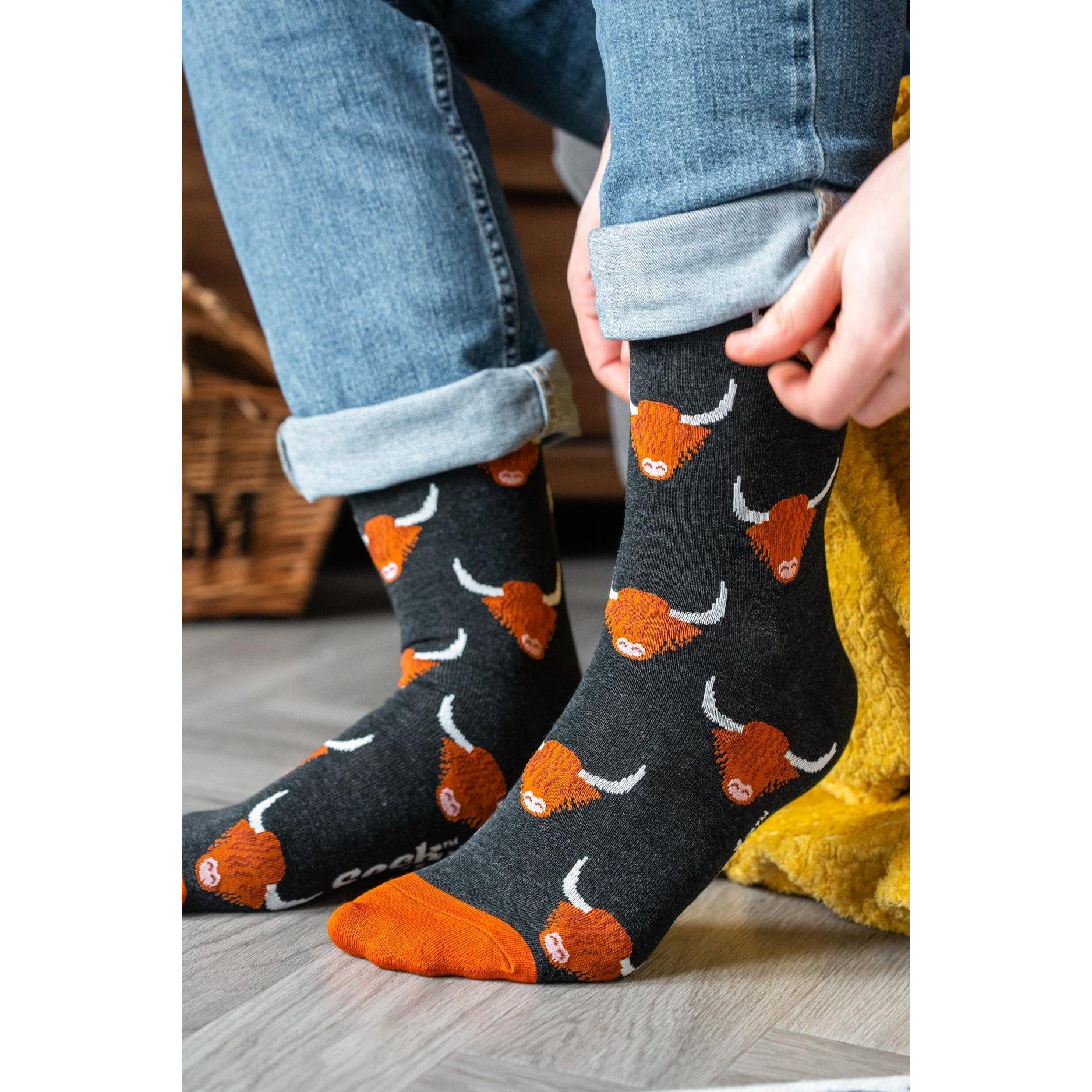 Men's black bamboo socks with orange Highland cow pattern, featuring orange toes and heel, casual and comfortable footwear.