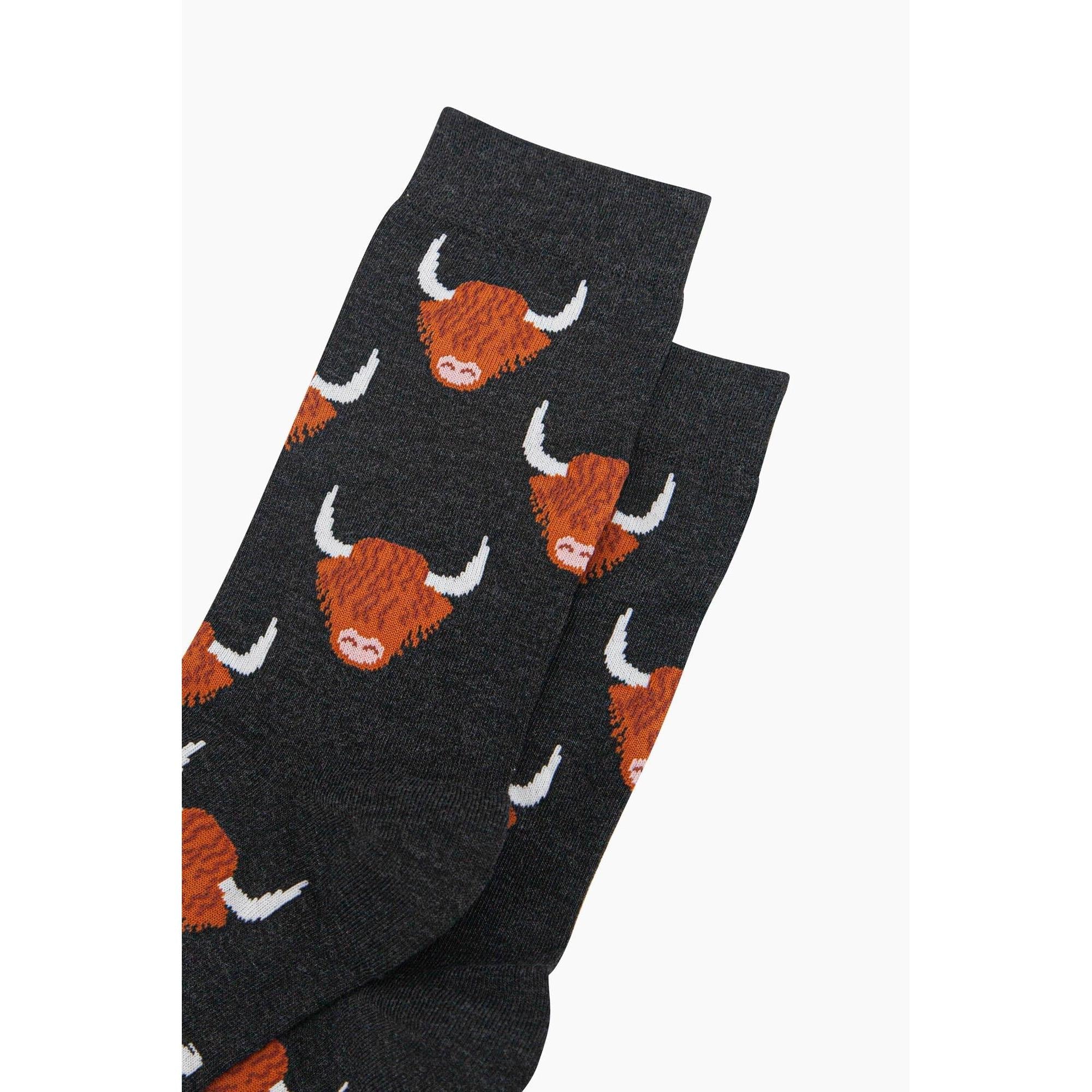 Men's black bamboo socks with Highland cow pattern, featuring white horns and brown cow faces.