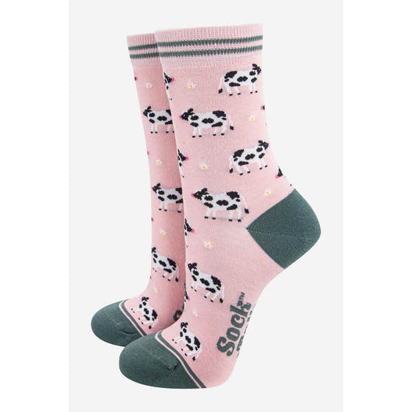 Women's pink bamboo socks with black and white cow print and small yellow dots, featuring green heel and toe details.