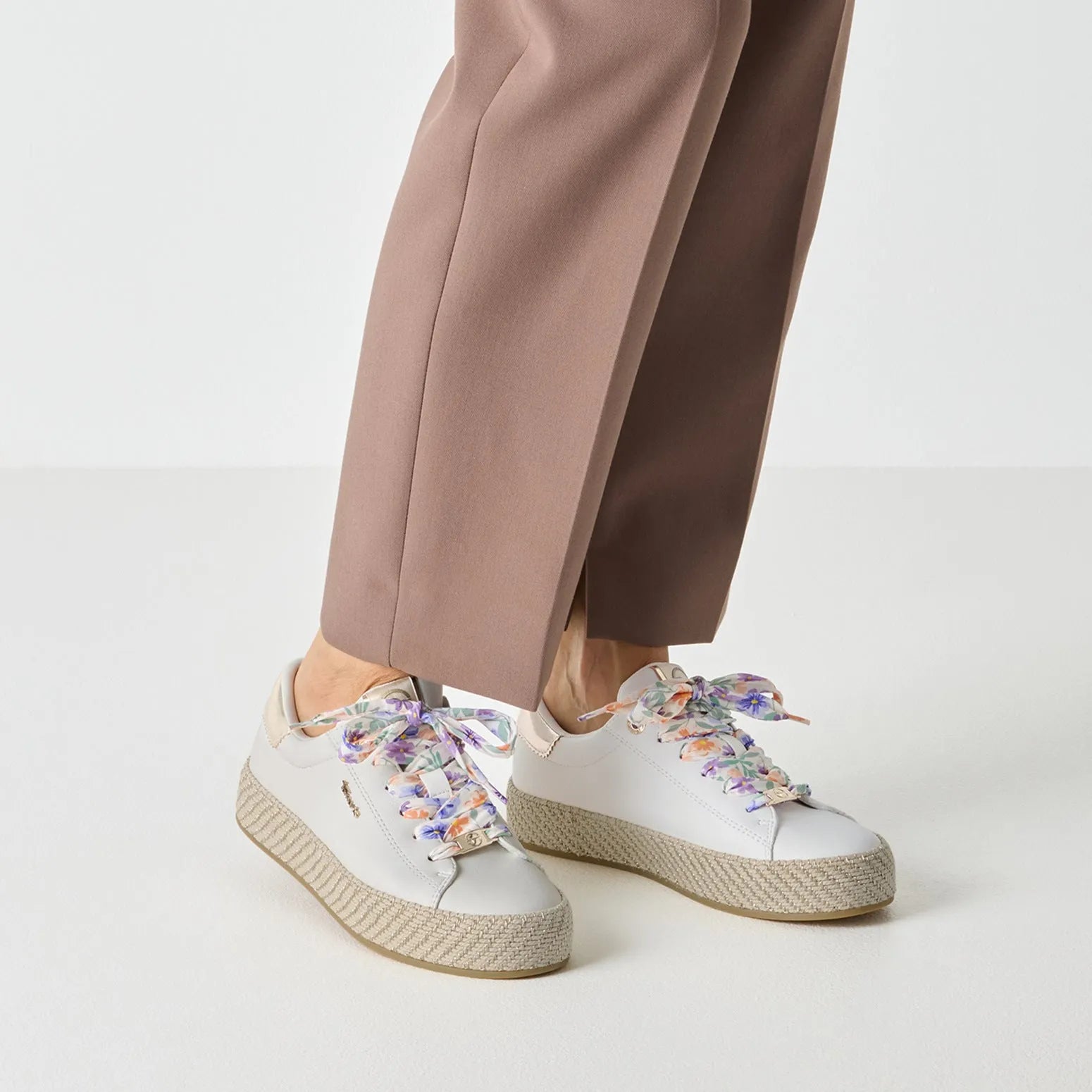 White lace-up shoes with floral-patterned satin ribbons, chunky beige sole, and smooth leather material.