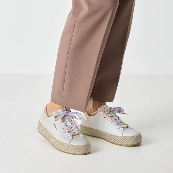 White lace-up shoes with floral-patterned satin ribbons, chunky beige sole, and smooth leather material.