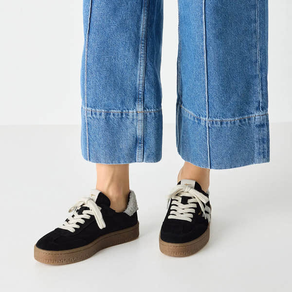 Tamaris Ladies black and beige leather and textile lace-up trainers with fur detail, chunky sole, and wide-leg denim jeans.