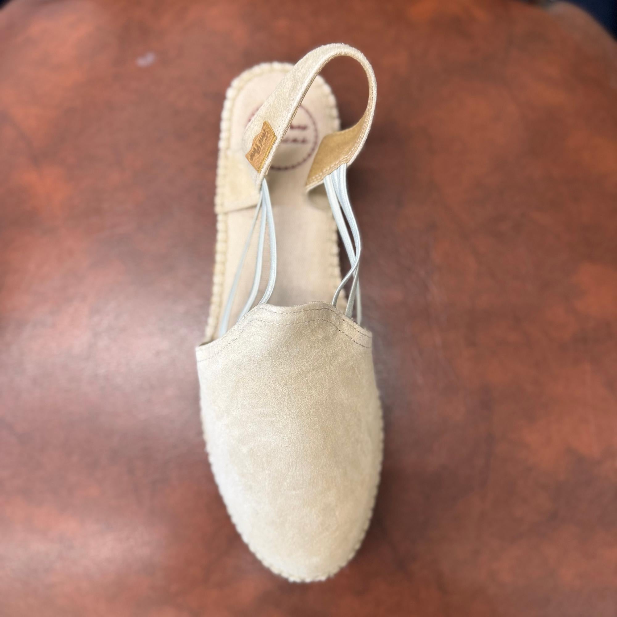 Toni Pons Nuria women's Spanish leather pull-on sandals with stone-colored upper and elastic straps on a wooden surface.