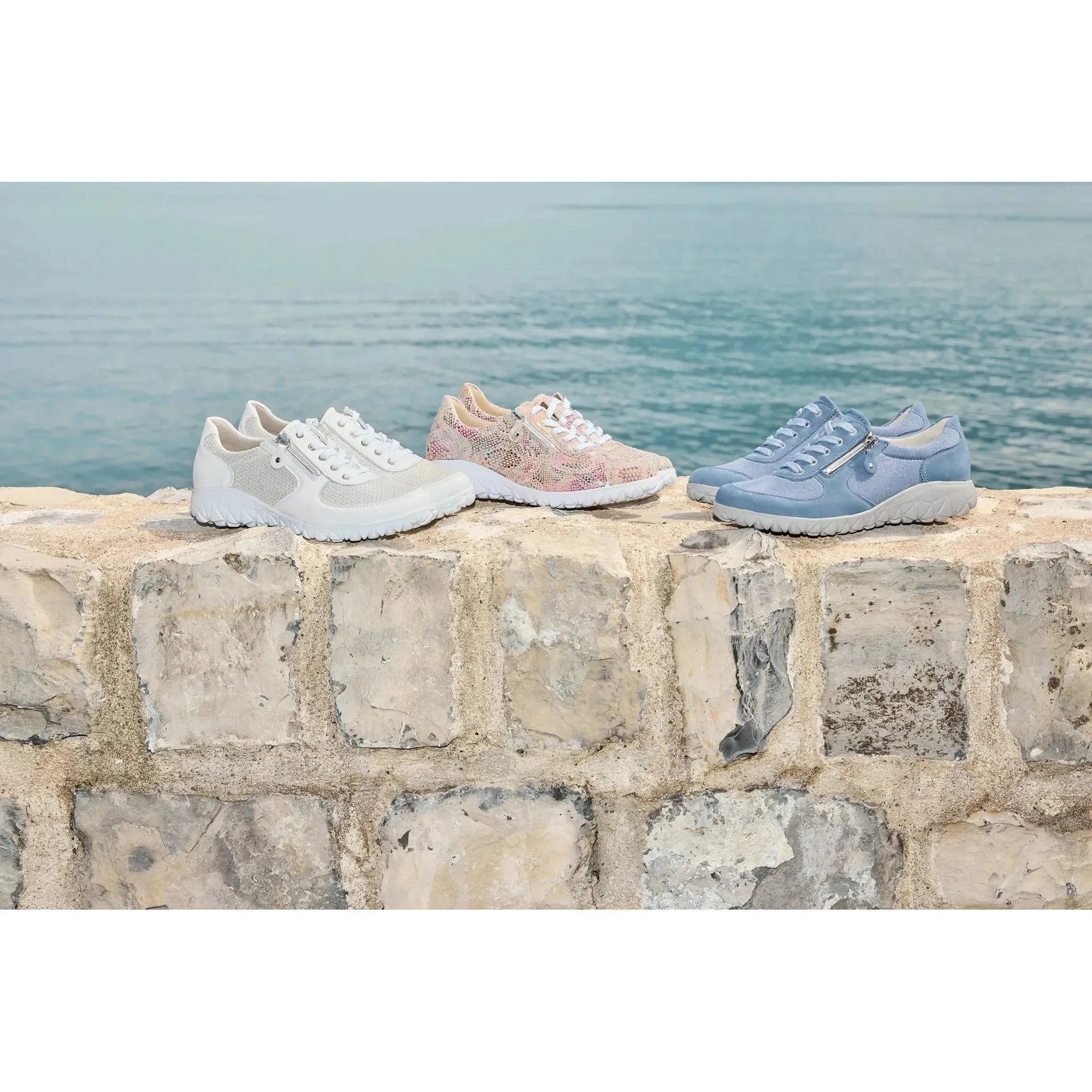 Waldlaufer H89001 Ladies wide fit denim nubuck sneakers with zip and lace fastening, soft cushioning, on a textured stone surface by the sea.